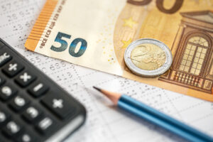 calculadora dinero y lapiz closeup sobre un fondo borroso scaled
